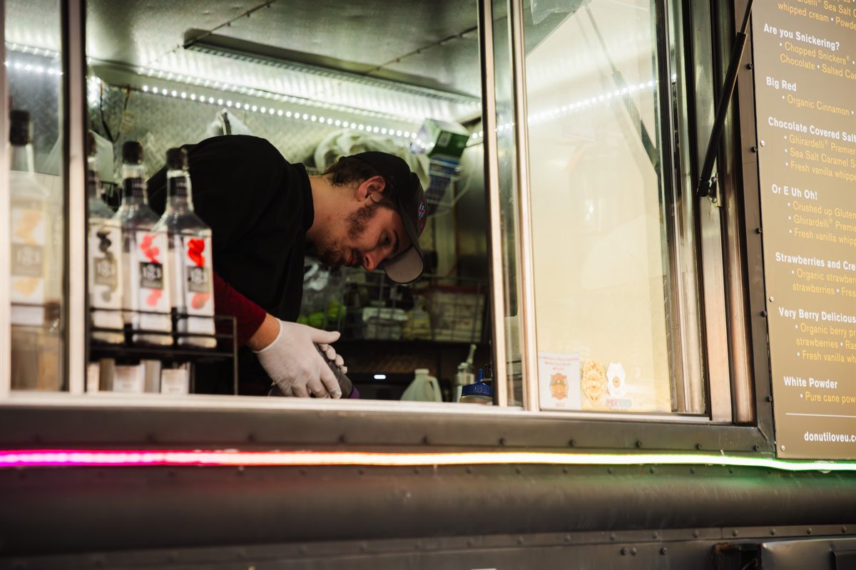 A team member making an order at the truck’s window, beside the flavour board.